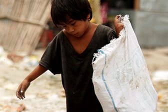 Ein philippinischer Junge sucht in einem Slum in Manila nach verwertbaren Dingen.