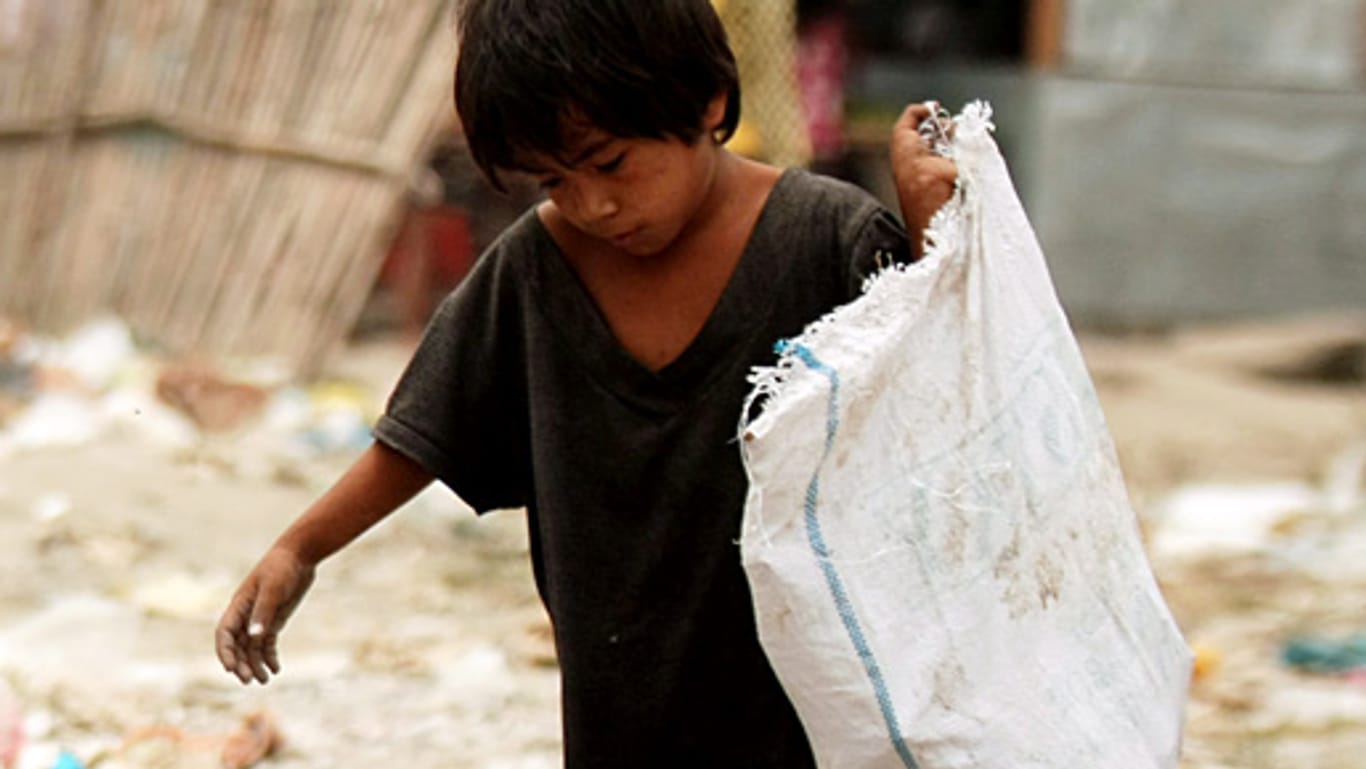 Ein philippinischer Junge sucht in einem Slum in Manila nach verwertbaren Dingen.