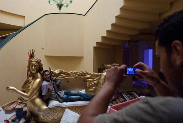 In der Villa der Gadaffi-Tochter Aischa posiert ein Kämpfer auf einem vergoldeten Sofa. Ein zweiter Rebell hält den Moment für die Nachwelt fest