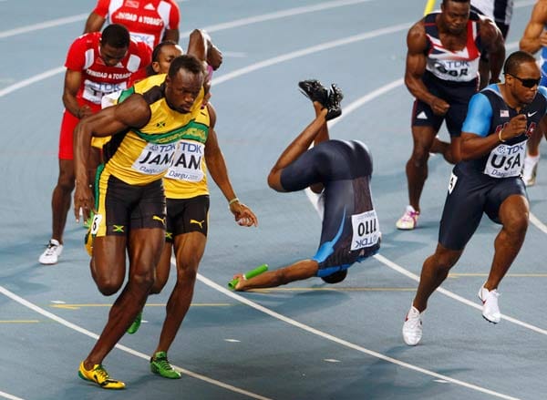 Usain Bolt übernimmt den Stab von Staffelkollege Yohan Blake, während der US-Amerikaner Darvis Patton unsanft auf der Bahn landet.