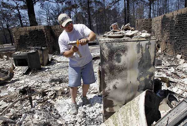 Ein Mann öffnet in seinem abgebrannten Haus einen feuerfesten Container. Viele Menschen haben alles verloren.