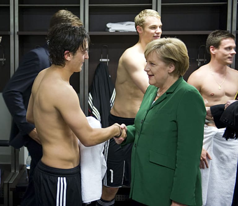 Auch zur deutschen Fußball-Nationalmannschaft pflegt Merkel innige Beziehungen. Hier schüttelt sie Nationalspieler Mesut Özil im Oktober 2010 in der Umkleidekabine die Hand. Zuvor hatte Deutschland im EM-Qualifikationsspiel die Türkei besiegt.
