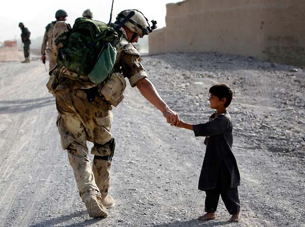 Die Soldaten werden daher vor ihrem Einsatz im Umgang mit der Bevölkerung geschult. Hier begrüßt ein kanadischer Soldat während einer Patrouille einen afghanischen Jungen.