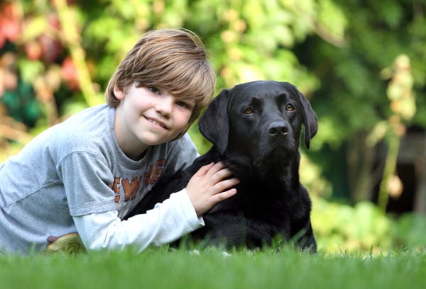 Der neunjaehrige Arnold Quass und seine Labradorhüendin "Lulu" liegen in Schwerin im Garten der Familie im Gras.