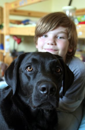 Der neunjaehrige Arnold und seine Labradorhündin "Lulu" im Kinderzimmer von Arnold.