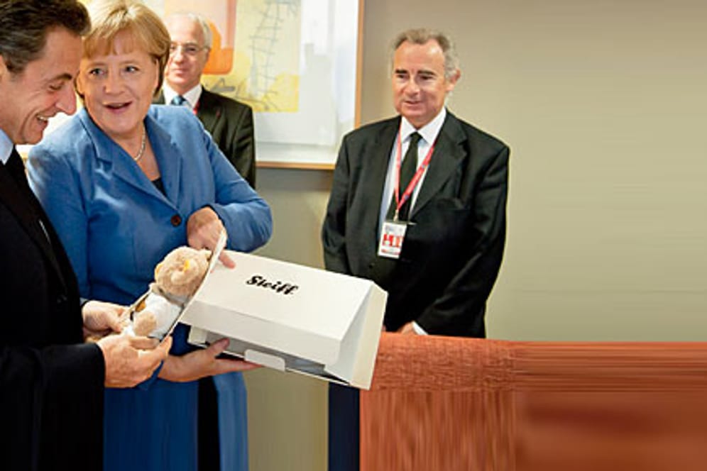 Angela Merkel überreicht Nicolas Sarkozy für seine kleine Tochter Giulia einen Teddybär.