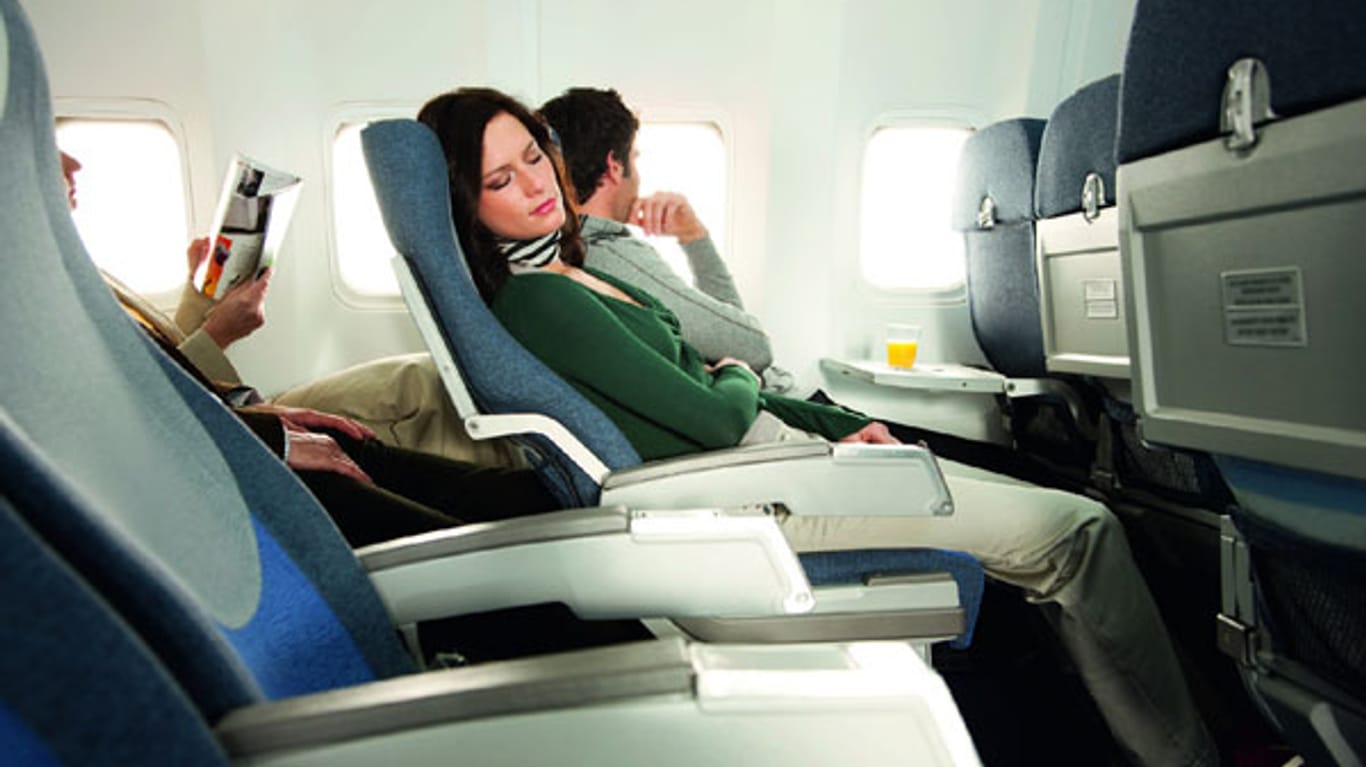 Eine Frau schläft im Flugzeug: Wer viel reist, sollte über eine Langzeit-Auslandskrankenversicherung nachdenken.