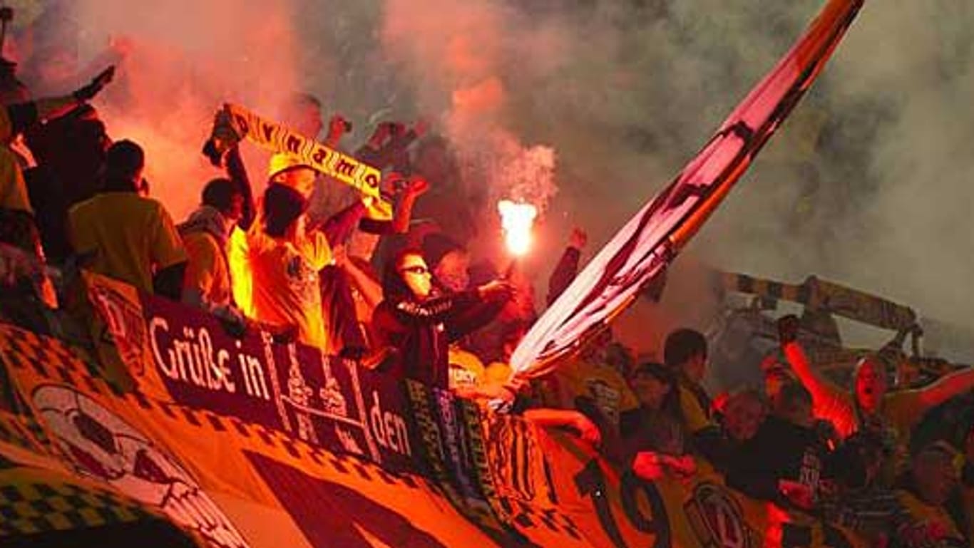 Fans von Dynamo Dresden zünden Bengalos beim Pokalspiel in Dortmund.