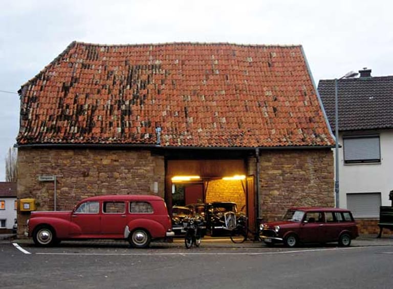 Das Dach dieser Garage wirkt etwas marode. Innen ist das Gebäude aber restauriert und die Oldtimer erstrahlen in hellem Licht.