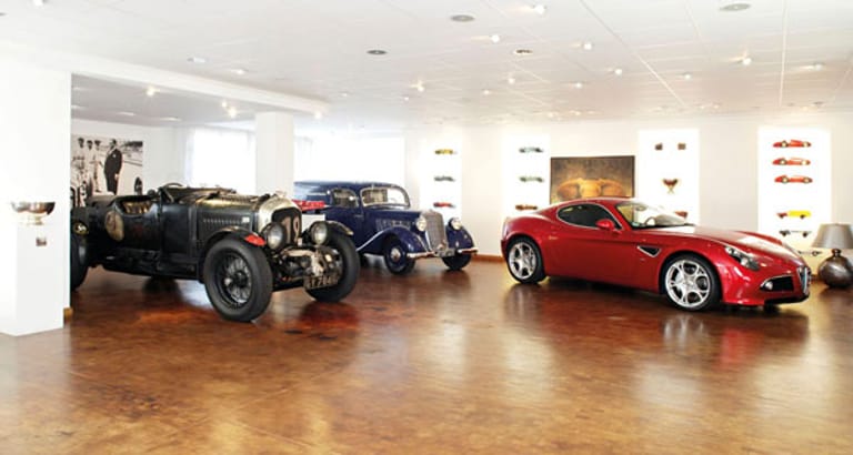 Diese Garage befindet sich in einem Büro. Ein Münchner Unternehmer lies sich eine Hebebühne an der Hauswand befestigen um seinen Bentley „Blower“ (v.l.), Mercedes 170 V Werkstattwagen, Alfa Romeo 8C Competizione hineinzufahren.
