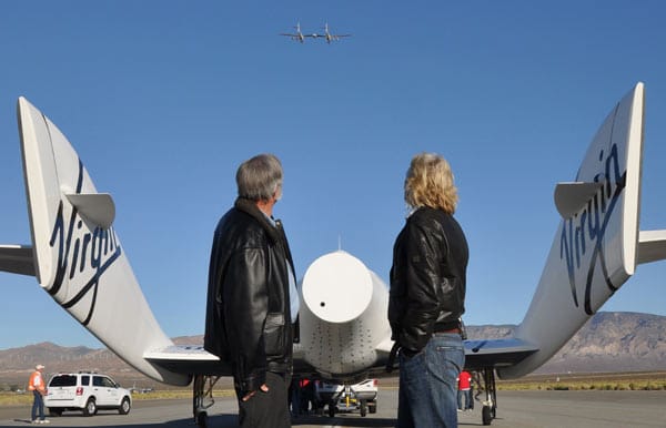 Richard Branson und Burt Rutan stehen hinter dem "SpaceShipTwo" nach der erfolgreichen Landung in der Mojave-Wüste. In der Luft ist "WhiteKnightTwo" zu sehen.