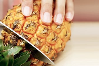 Eine Ananas wird aufgeschnitten.