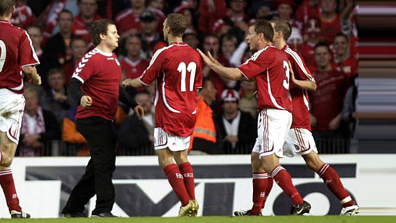 Mehrere dänische Nationalspieler halten den auf den Platz gestürmten Fan zurück.