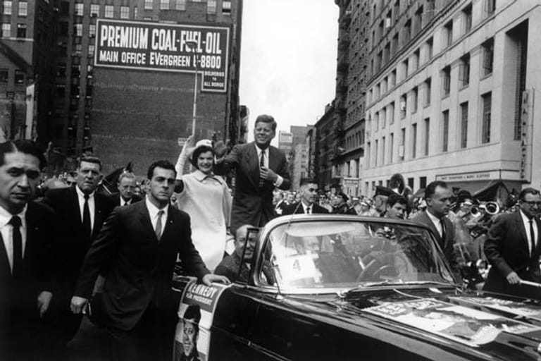 John Fitzgerald "Jack" Kennedy, geboren am 29. Mai 1917, fährt im Oktober 1960 als demokratischer Kandidat für die US-Präsidentschaftswahl am 8. November mit seiner Frau Jacqueline durch die Straßen von New York. Kennedy gewinnt die Wahl und wird am 20. Januar 1961 als 35. Präsident der USA vereidigt.
