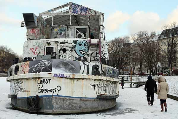 Spaziergänger gehen am Urbanhafen in Berlin Kreuzberg auf dem zugefrorenen Landwehrkanal neben dem Theaterschiff über das Eis.