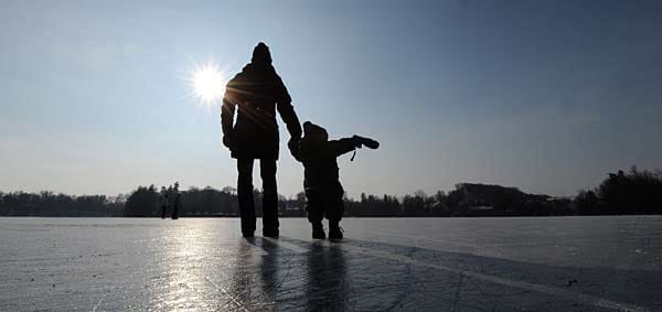Eine Mutter und ihr Sohn gehen bei Temperaturen von Minus 15 Grad in Weßling über den zugefrorenen See.