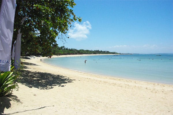 Im Schatten der Palmen können Gäste des The Laguna Luxury Collection Resort & Spa auf Bali entspannt den langen Strand entlang schlendern.
