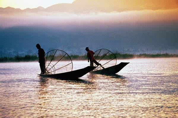 Aus dem Nichts tauchen zwei Fischerboote auf, zwei Männer stoßen mit ihren kubischen Flechtkörben ins seichte Wasser. Die Söhne des Sees, so nennt sich das Volk der Intha, leben nicht am See, sondern im See, in perfekter Anpassung an ihre Umgebung.