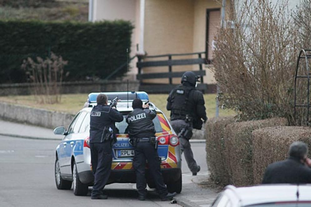 Polizisten umstellen das Haus des Todesschützen von Weilerbach