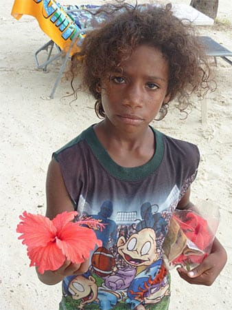 Kleiner Junge aus Haiti, der Blumen für wenige Cent an einem Touristenstrand in der Dominikanischen Republik verkauft. Solche Kinder haben keine Rechte.