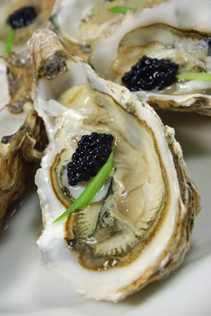 Zwei Delikatessen treffen aufeinander: Hier die Kombination von schwarzem Kaviar und einer frischen Auster.