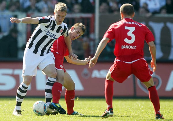 St. Paulis Marius Ebbers (li.) schirmt den Ball geschickt gegen Uwe Hünemeier ab. Ivica Banovic schaut interessiert zu.