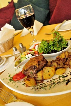 Die Abendessen in der Lodge sind ein Genuss. Den Gästen wird Oryx-Steak mit Kartoffelgratin und Salat serviert. Dazu trinkt man Rotwein aus Südafrika.