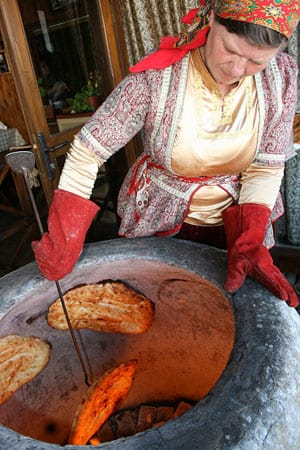 Ganz traditionell: In der Altstadt von Baku backen Frauen in Trachten in einem Steinofen Fladenbrot mit Sesamkörnern.