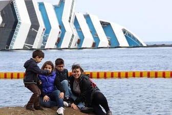 Schaulustige posieren vor dem havariertem Kreuzfahrtschiff "Costa Concordia".