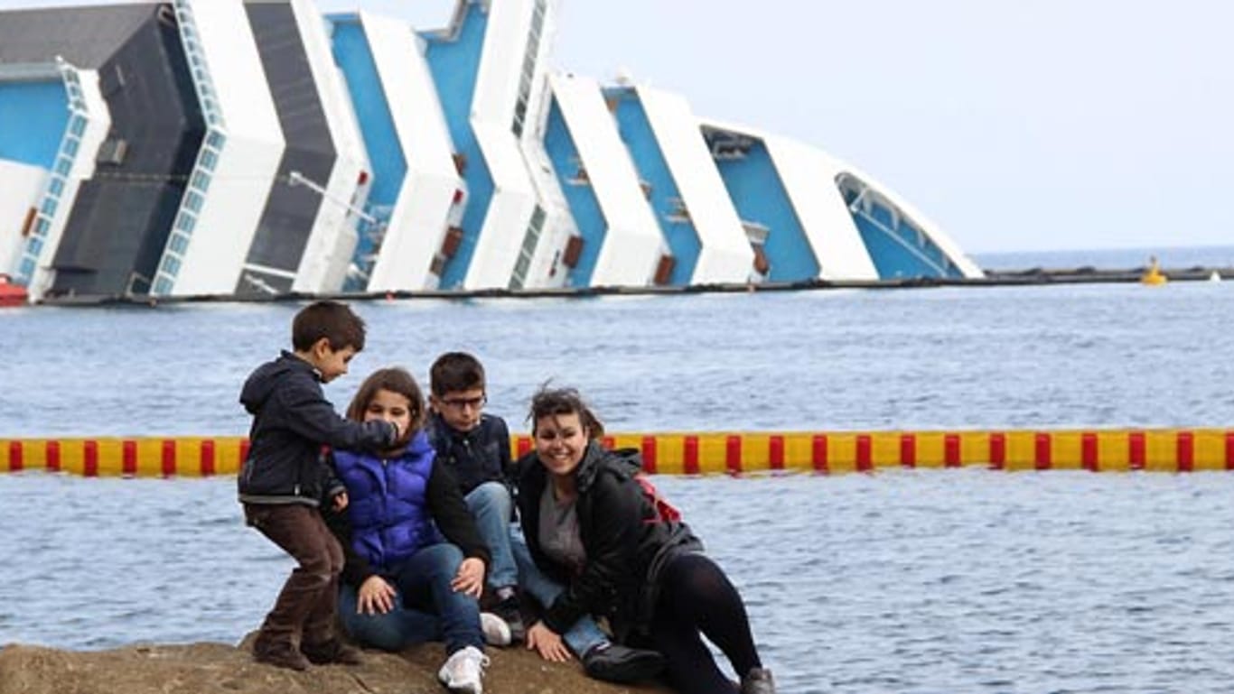 Schaulustige posieren vor dem havariertem Kreuzfahrtschiff "Costa Concordia".