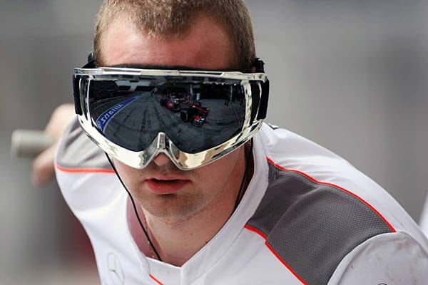 Der Bolide von Jenson Button spiegelt sich in der Brille eines McLaren-Mechanikers.