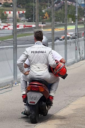 "Taxi!" Schumacher wird mit einem Motorroller zurück ins Fahrerlager gebracht.