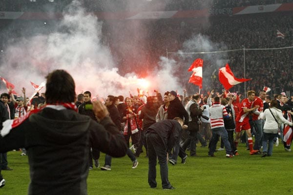 Während die Fans auf den Platz strömen, suchen die Spieler (wie rechts Düsseldorfs Jovanovic) den Notausgang.