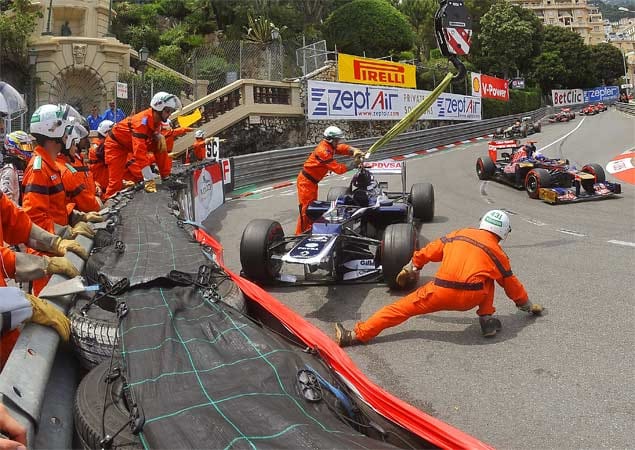 Gefährliches Spiel für den Streckenposten: Nach dem "Abflug" von Pastor Maldonado in seinem Williams müssen die Helfer viel Geschick und Gelenkigkeit beweisen, um nicht von den vorbeifahrenden Formel 1 Boliden erfasst zu werden.