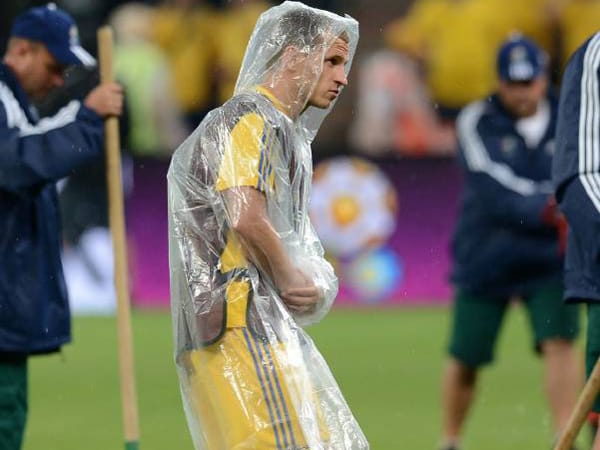 Der ukrainische Nationalspieler Olexandr Aliyev schützt sich während der EM-Partie gegen Frankreich vor dem starken Regen mit einem Cape. Seine Körperhaltung erinnert dabei an eine alte Frau.