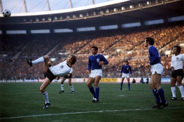 11. Oktober 1975: Bernd Hölzenbein (li.) akrobatisch am Ball gegen zwei Griechen, Erwin Kostedde (re.) schaut zu. Auch im Rückspiel der EM-Qualifikation im Düsseldorfer Rheinstadion gelingt der Mannschaft von Trainer Helmut Schön kein Sieg. Am Ende steht es 1:1, das einzige Tor erzielte der heutige Bayern-Coach Jupp Heynckes.