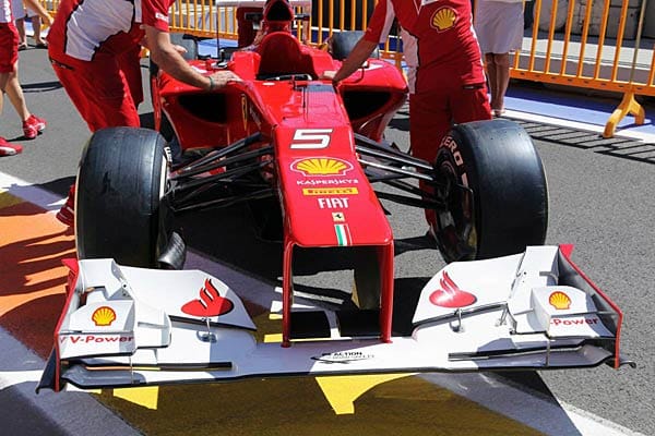 Ferrari-Mechaniker schieben einen Boliden des Teams durch die Boxengasse.