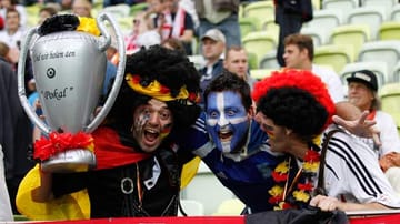 Ein griechischer und zwei deutsche Fans wetteifern schon vor der Partie.