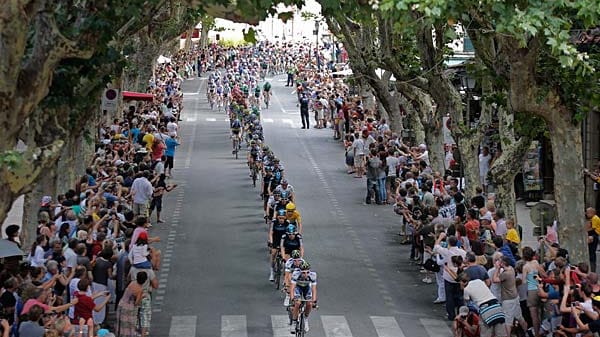 Allee-Blick: Wie an einer Perlenkette aufgereiht, fährt das Peloton durch einen Ort während der 13. Etappe.