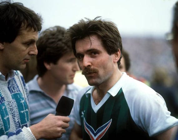 Jörg Wontorra und Mirko Votava ahnen es noch nicht: In der Saison 1985/86 triumphiert der FC Bayern, weil Michael Kutzop am vorletzten Spieltag den berühmtesten Elfmeter der Bundesligageschichte verschießt.