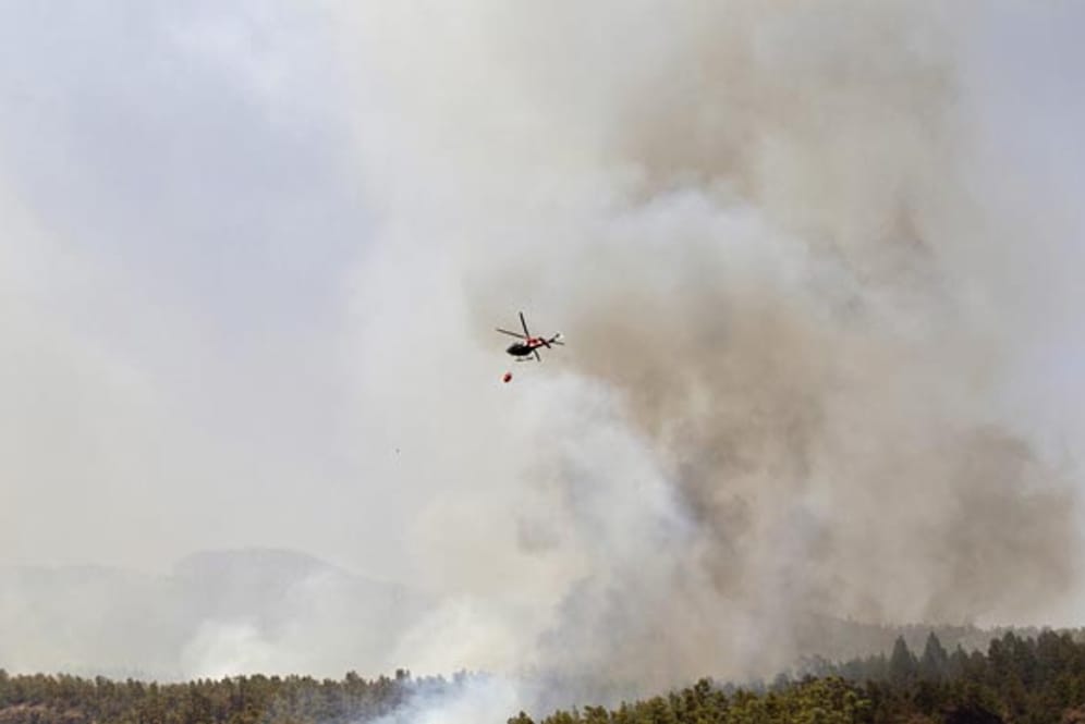 Ein Löschhubschrauber fliegt über ein betroffenes Gebiet im Süden der Kanareninsel Teneriffa.