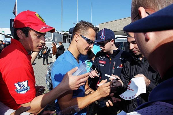 Volksnah gibt Michael Schumacher (Mitte) geduldig Autogramme.