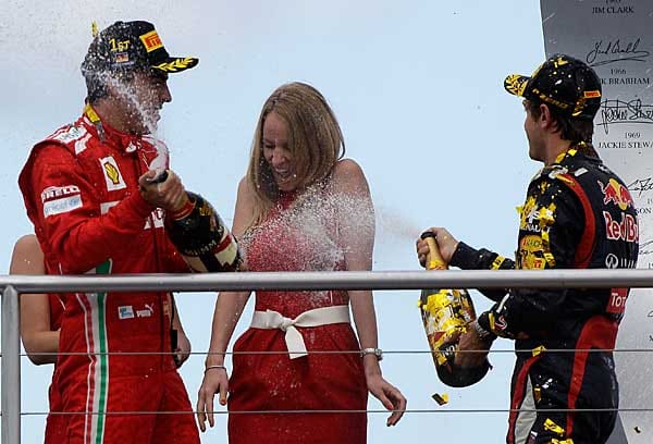 Fernando Alonso und Sebastian Vettel verpassen einem Grid Girl eine Champagnerdusche.