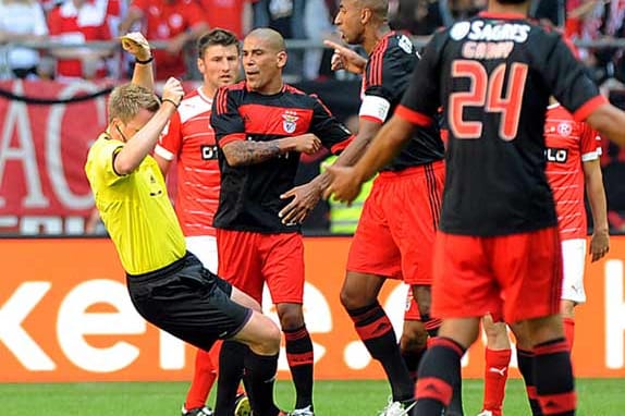 Schiedsrichter Christian Fischer (li.) wird im Testspiel in Düsseldorf von Benfica-Kapitän Luisao (2.v.r.) umgestoßen und fällt zu Boden.