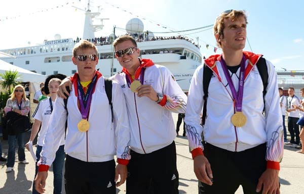 Die Ruder-Olympiasieger Karl Schulze (v. li. n. re.), Andreas Kuffner und Philipp Wende präsentiren ihre Goldmedaillen.