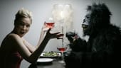 Frau mit Mann in Gorilla-Kostüm am Tisch