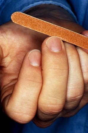 Nachdem Sie die Nägel zunächst mit einem Nagelknipser geschnitten haben, beginnt das Feintuning: Feilen Sie Ihre (trockenen) Fingernägel von der Mitte zu den Seiten. Es sollte nur in eine Richtung und seitlich nicht zu tief gefeilt werden, da der Nagel mit der Kuppe abschließen soll.