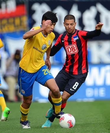 Braunschweigs Chengdong Zhang (li.) führt den Ball an Marcel Ndjeng von Hertha BSC vorbei.
