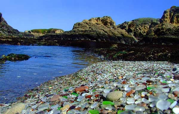 Der Glass Beach (deutsch: Glas Strand) besteht nämlich bei näherer Betrachtung nicht aus Kieselsteinen, sondern aus abgeschliffenem Glas, das mal weiß, rot oder grün am Boden schimmert.