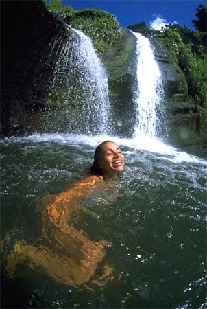 Eine Frau schwimmt in den Concord Wasserfällen. Diese zählen neben den Annendale und den Seven Sisters Waterfalls zu den spektakulärsten Grenadas.